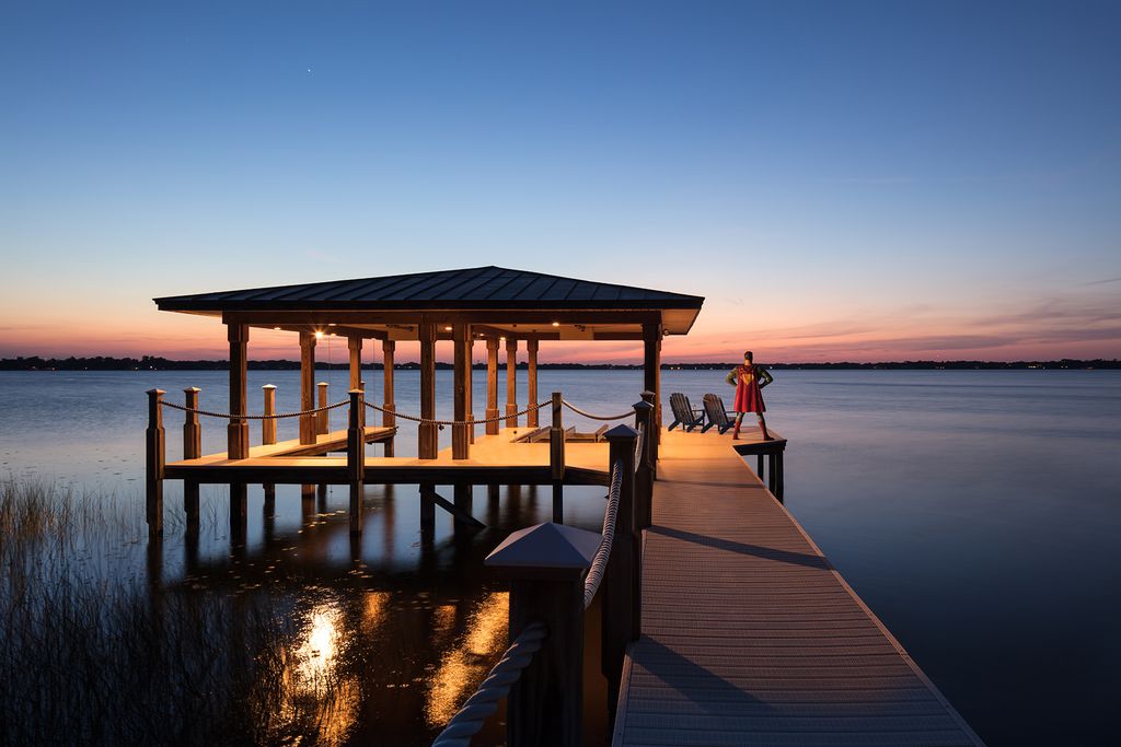 Superman standing at the end of an empty dock at sunset