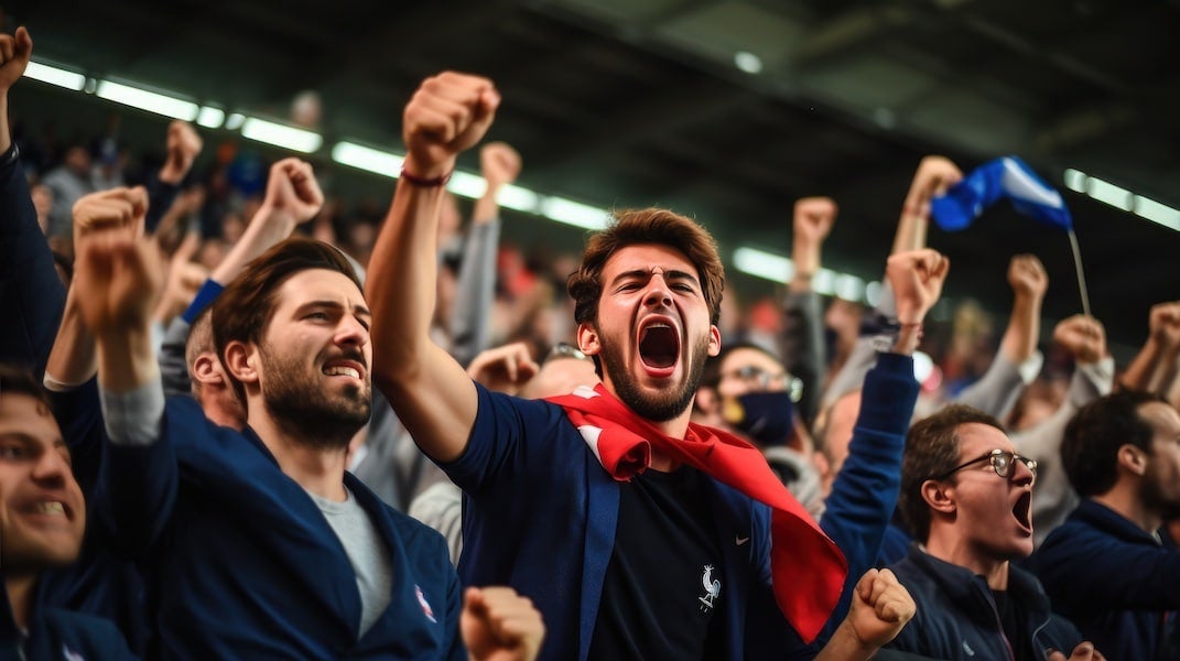 Stadium of people with their hands in the air, screaming and cheering.