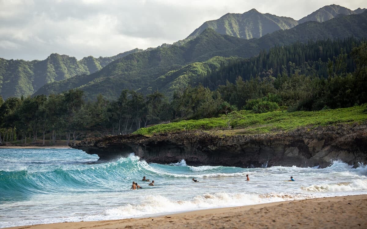 people swimming near shore with waves during daytime