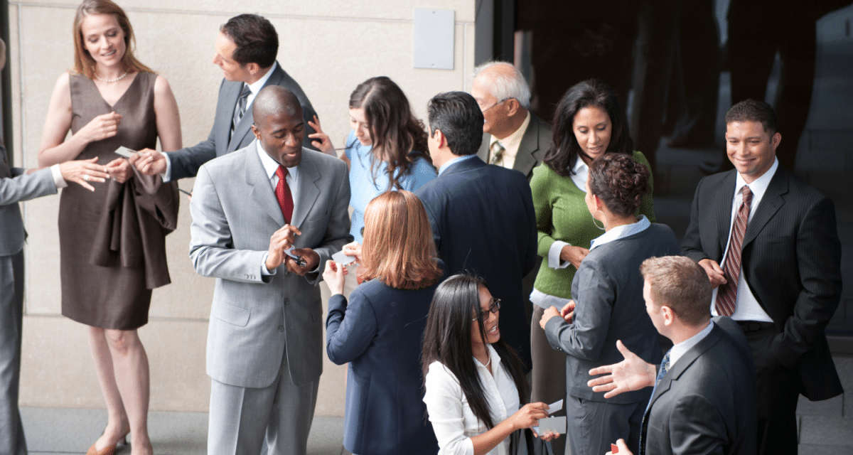  Image of a group of professionals at an outdoor networking event, talking and exchanging business cards.