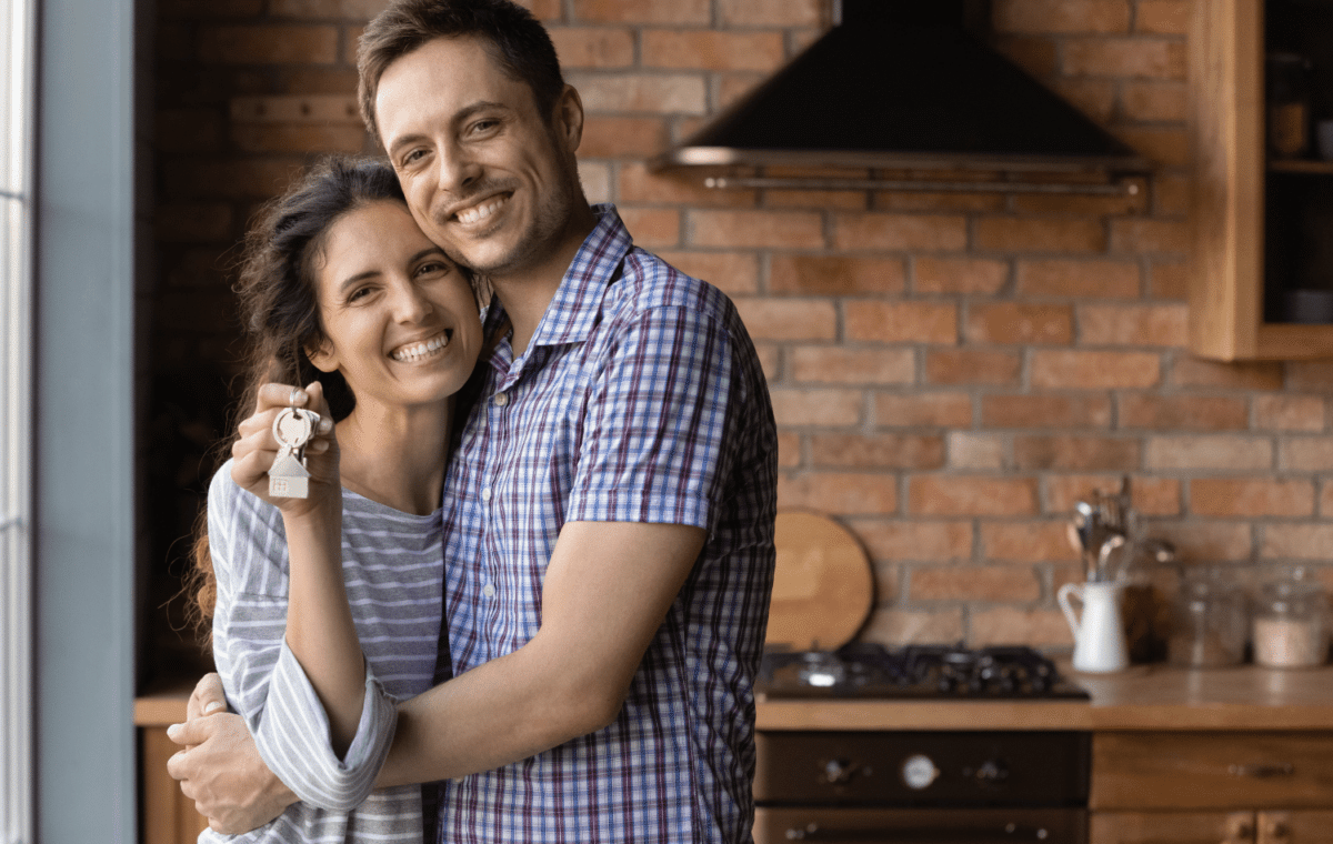 Young couple smiling and holding up a set of house keys