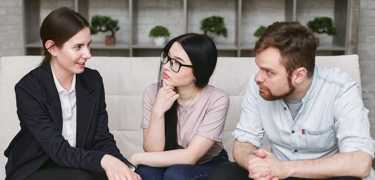 Female real estate agent talking with clients, a young man and woman couple.