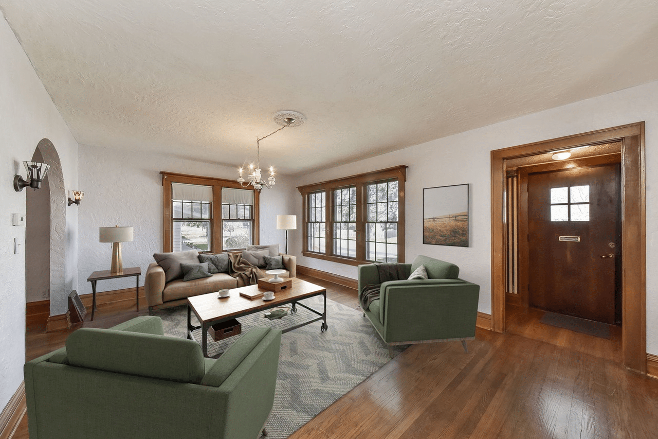 A spacious living room with large windows, sofa sets, and an arched doorway to the left