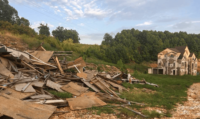 A pile of debris alongside an abandoned McMansion.