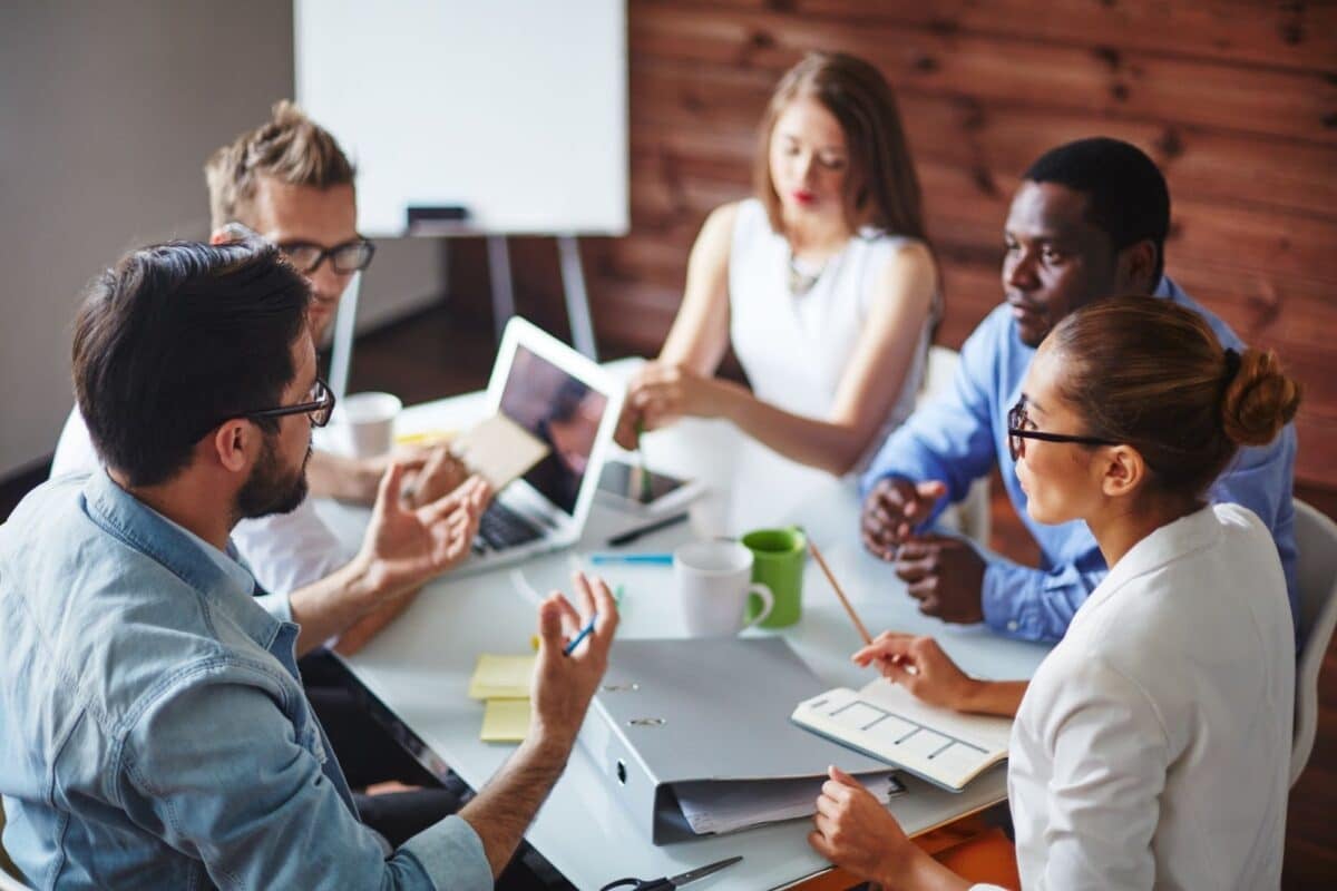 Five people in a meeting room discussing ideas