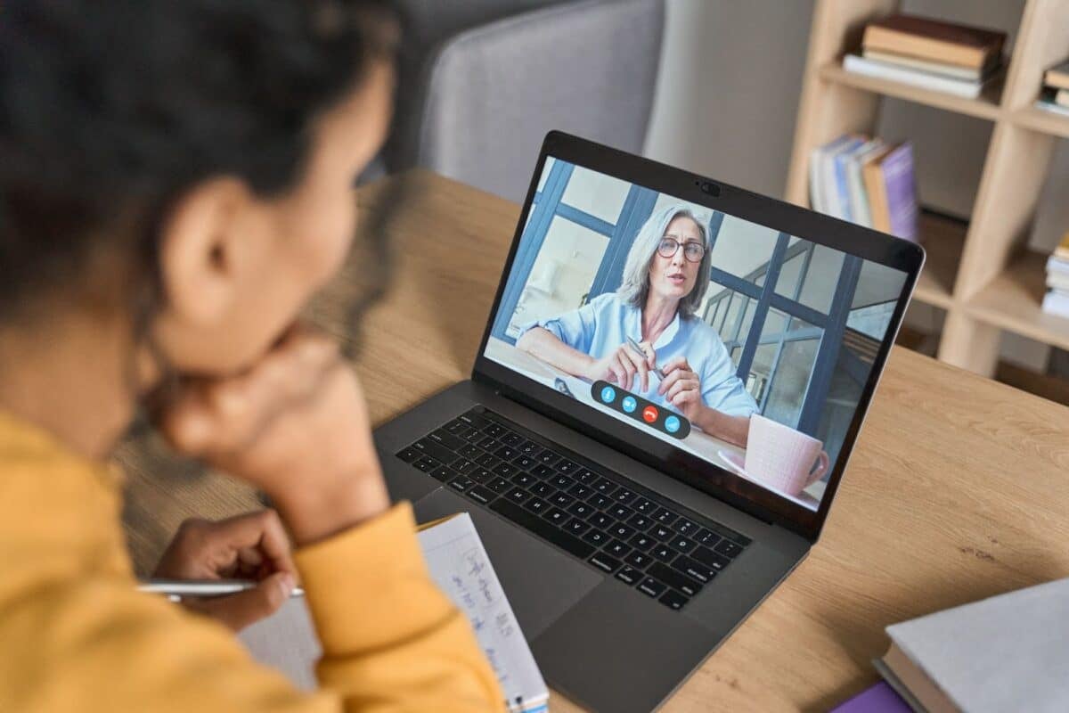 Over shoulder view of a female student attending a virtual class at home