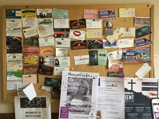 A cork bulletin board covered in business cards and flyers.