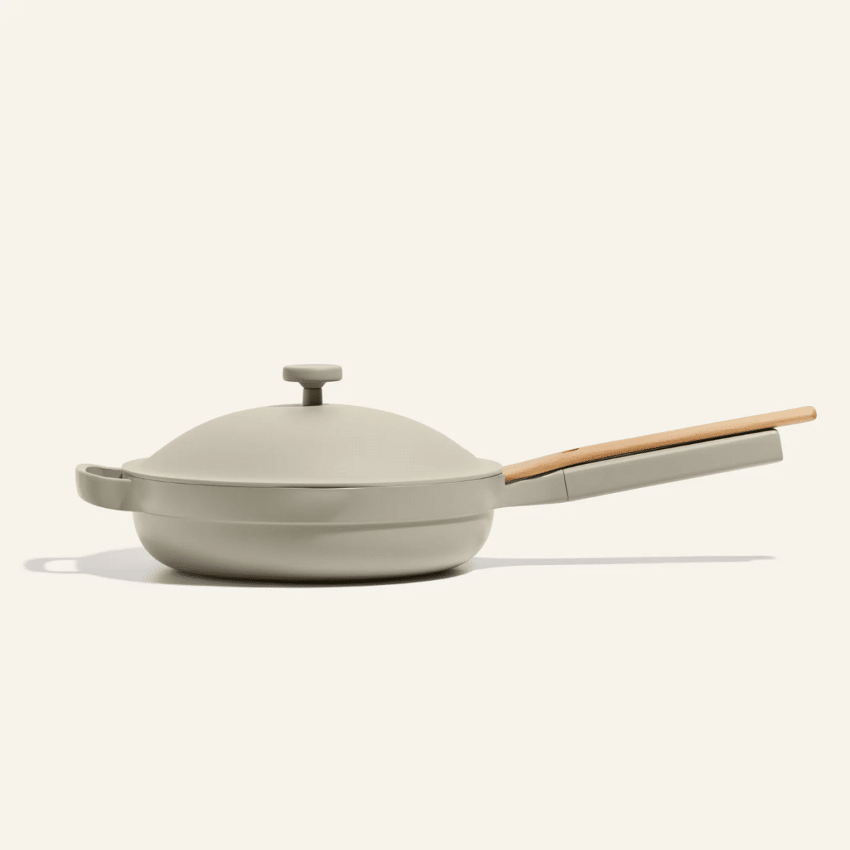 Grey pan with a lid and wooden spoon on pan's handle