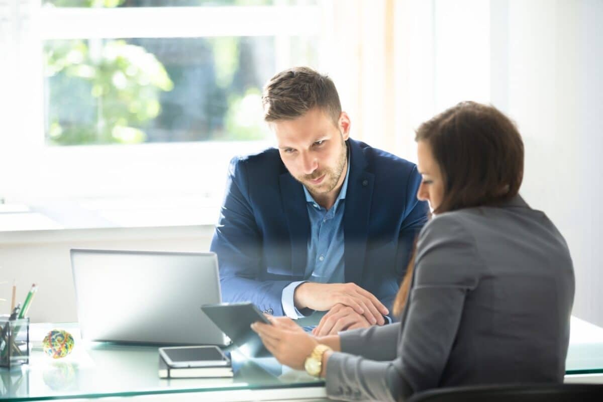 A real estate broker and an agent using a tablet during meeting