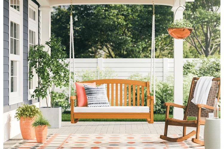 A porch swing and rocking chair outside a house