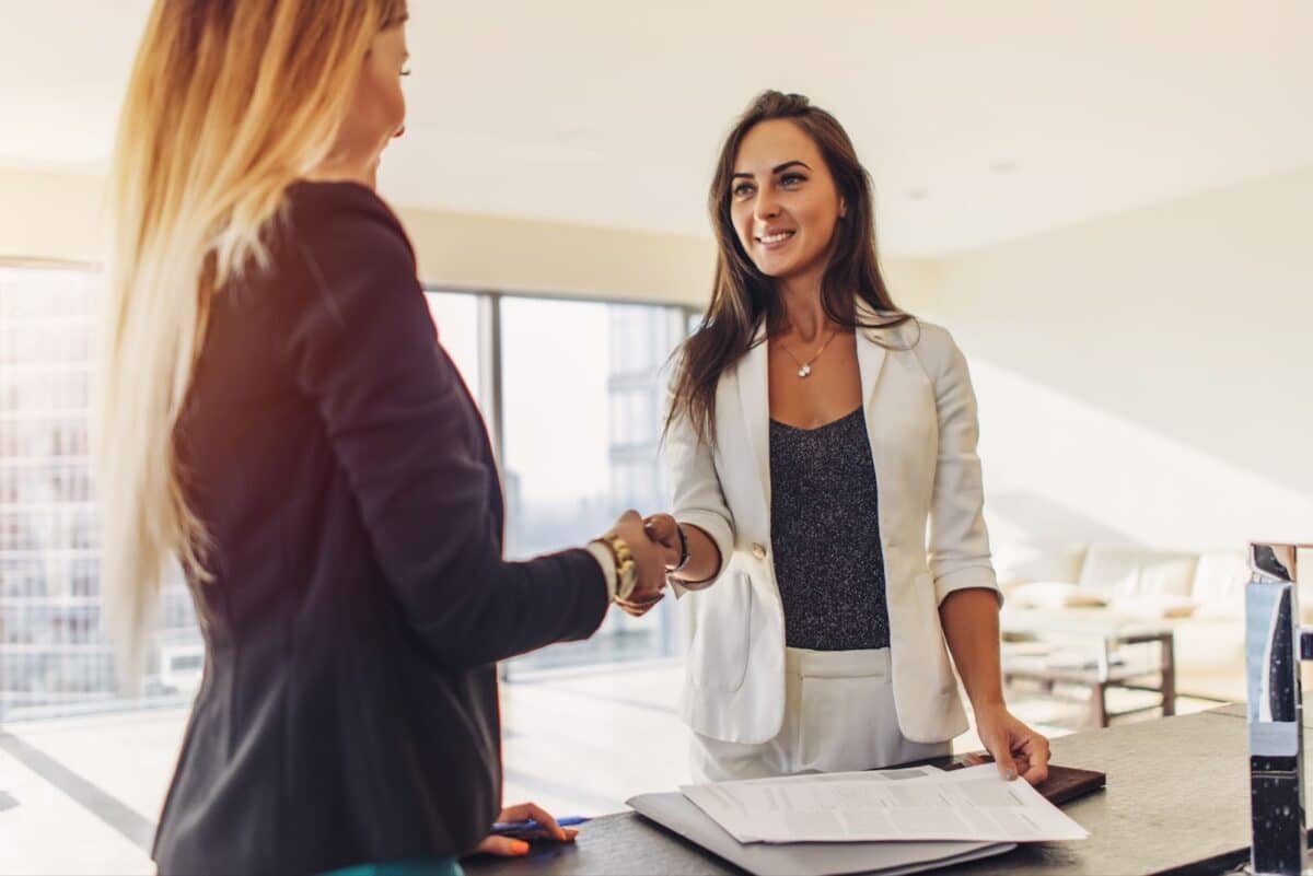 Female client shaking hands with a real estate agent after signing a contract