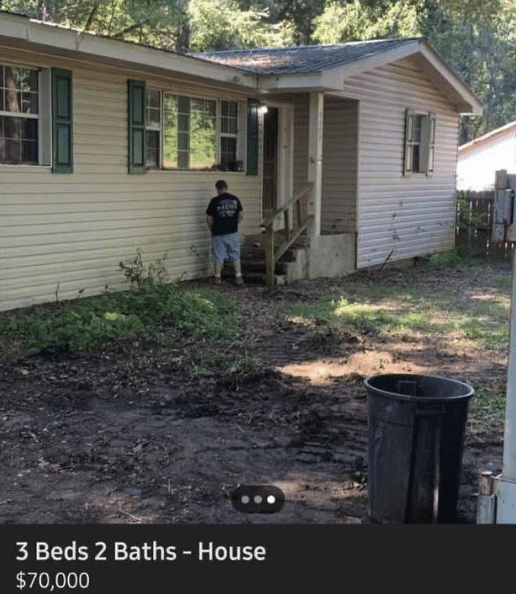 Exterior of a house with a man standing near the stairs, presumably relieving himself on the side of the house.