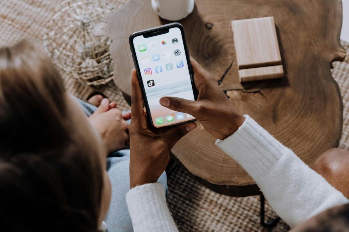 two people looking at a cell phone with apps in front of a coffee table.