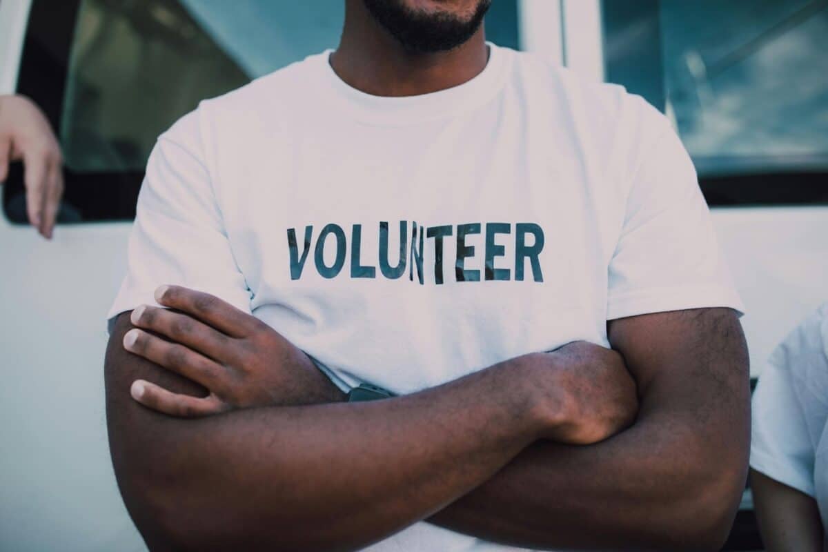 Picture of a man with his arms folded with a shirt on that says volunteer.