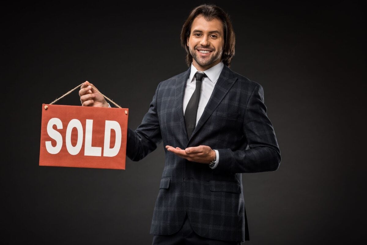 Real estate agent holding a sold sign.