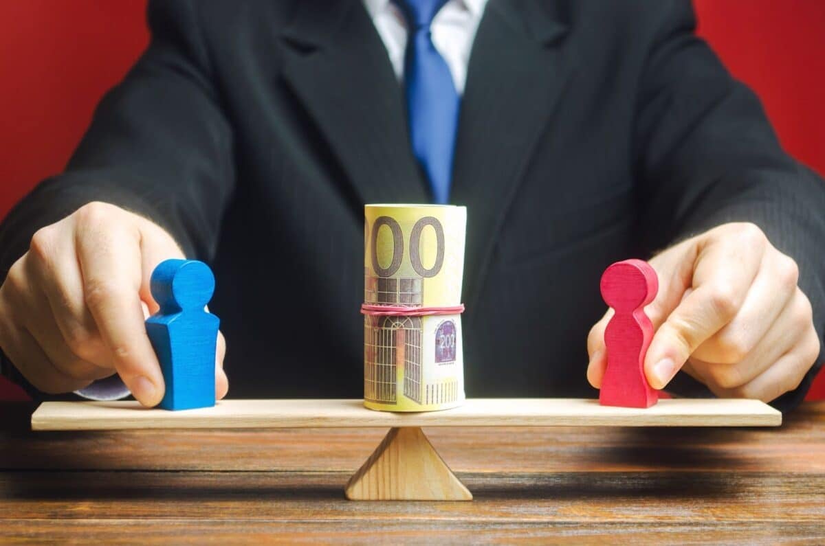 Man balancing wooden dolls on beam with money in between them.