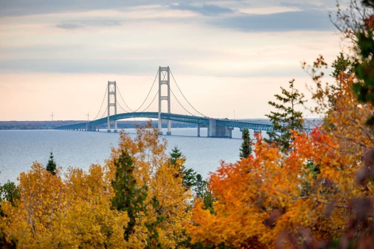 Aerial view of the Mackinac Bridge in Michigan, surrounded by vibrant fall colors of the forests.