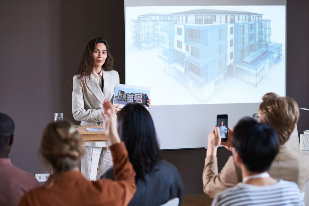 Businesswoman presenting modern building at seminar.