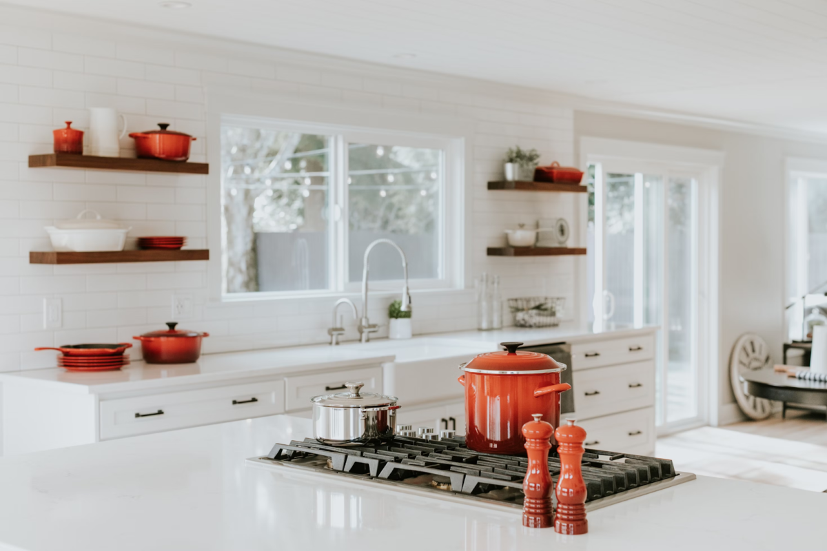 A white kitchen with a salt and pepper mill set, cooking pots, and stove