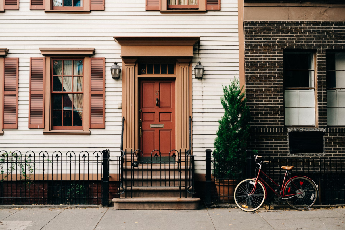 A home's clean front entrance with a large potted plant and bicycle on the side