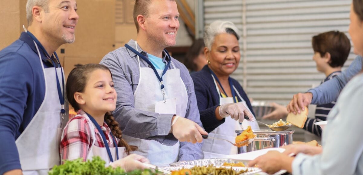 A group of men, women, and children serving food to the needy.