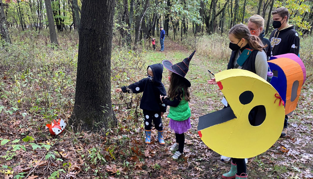 Kids in Halloween costumes on a scavenger hunt in the woods.