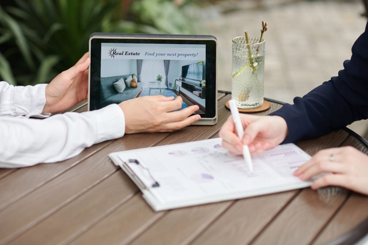 Two people looking at properties on iPad and writing projections on clipboard.