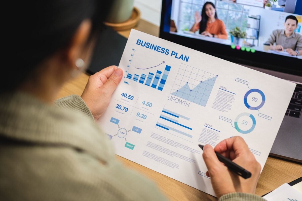 Woman in a videoconference business meeting with colleagues using a laptop at home.