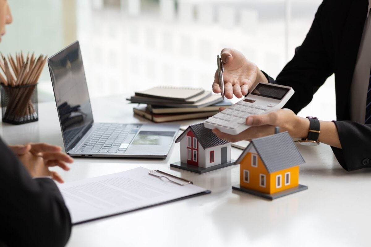 Real estate agent holding a calculator, presenting a price quote to an investor