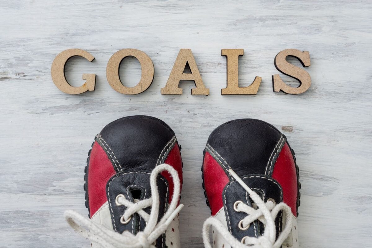 The word "GOALS" in wooden letters on a marble floor with sneakers below it.