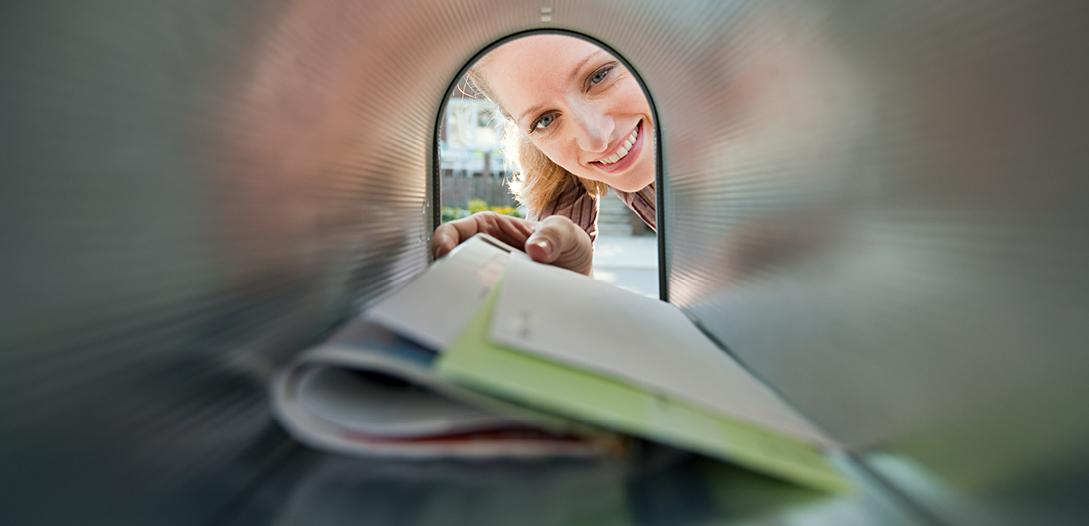 Woman looking in mailbox and removing her mail.