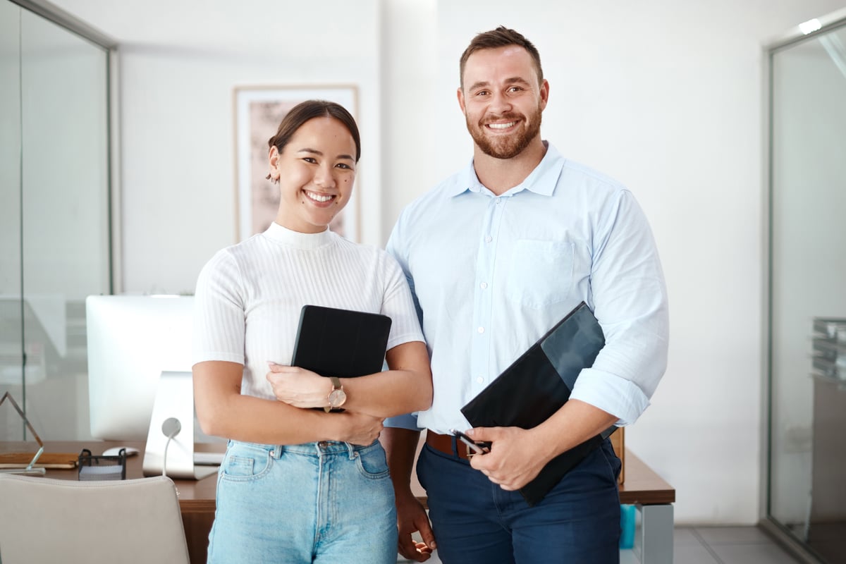 Two business people in office holding a tablet and folder