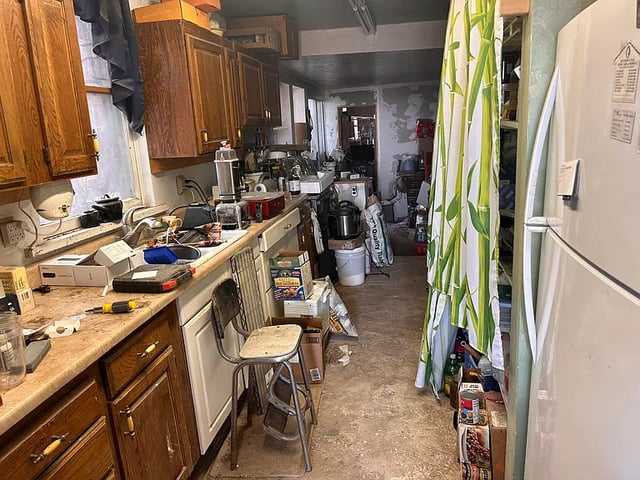 A kitchen with garbage and clutter all around.