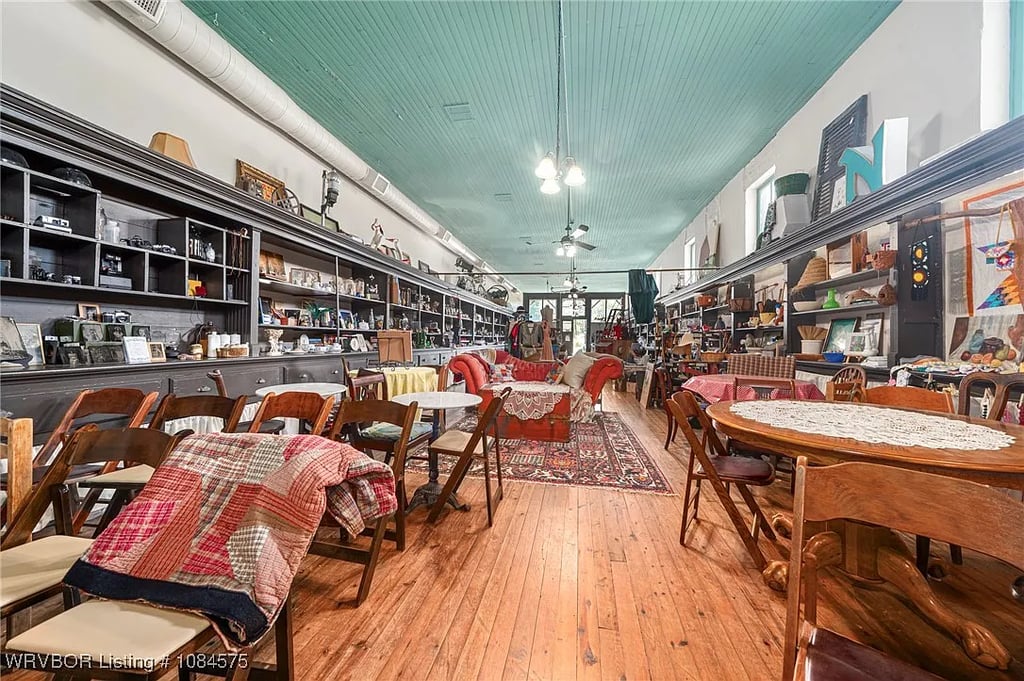 The inside of they stop, covered in historic wooden chairs and vintage items. The floor is wood, and the ceiling is a bluish green.