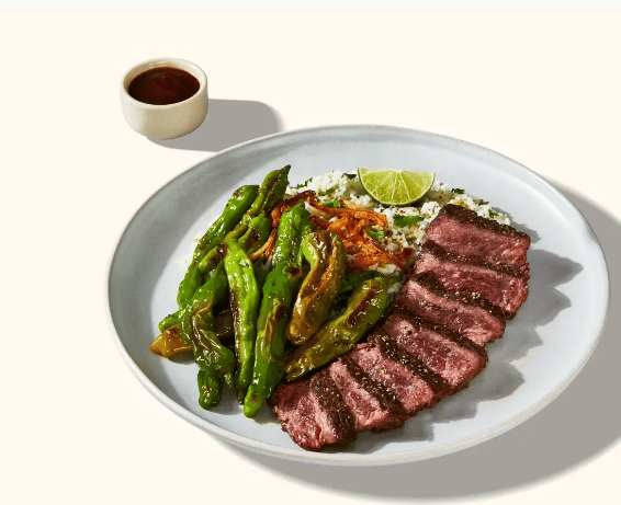 A plate of meat with greens and rice.