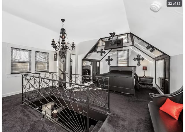 A bedroom with a gothic chandelier and spiderweb railing.