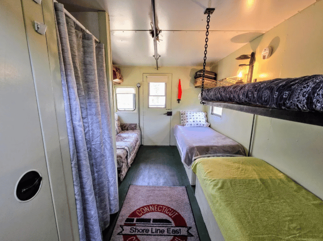 The bedroom inside the train with four beds, including one hanging from chains.