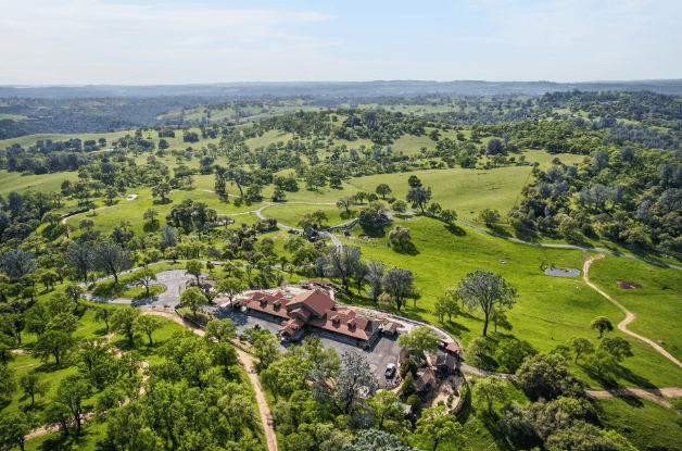 Aerial of a home with acres of green land around it.