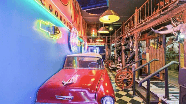 Room with half of a red hot rod and saloon theming.