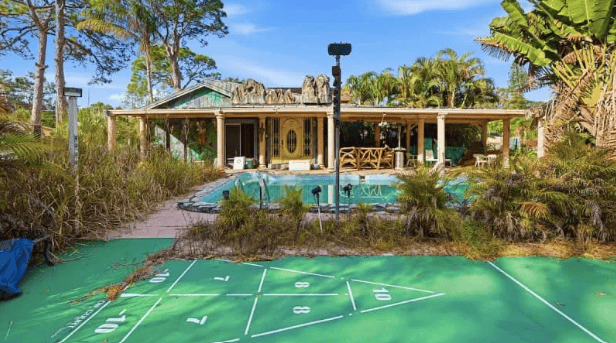 Backyard of the property with a lagoon style pool and shuffle board court.