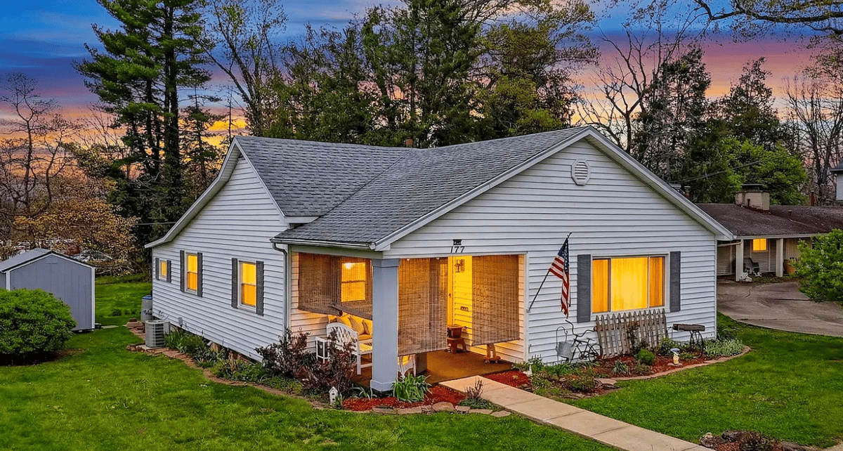 A white home in the evening with light coming through the windows.