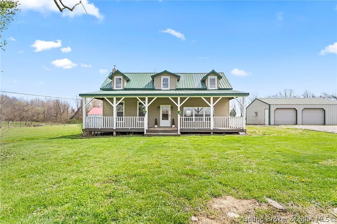 A home on a field with a front porch and green roof.